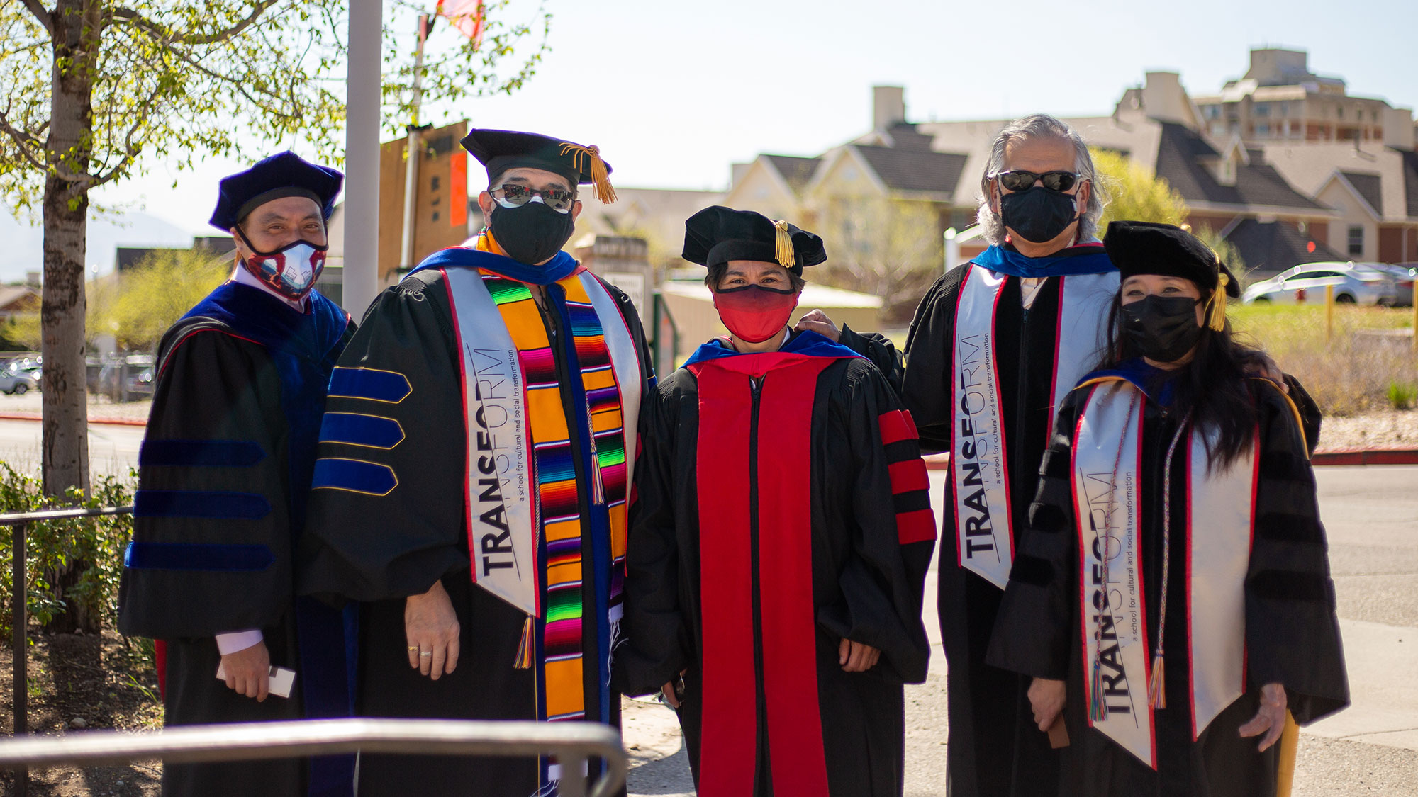 group of faculty and staff pose in a group wearing their graduation regalia