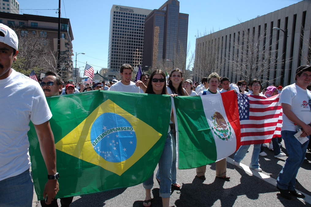 people marching while holding the Brazilian, Mexican, and American national flags